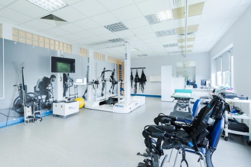 Sala rehabilitacyjna z robotem do terapii chodu i specjalistycznym sprzętem medycznym. 