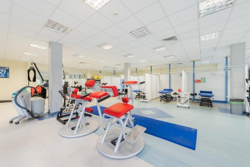Strefa ćwiczeń z urządzeniami do treningu funkcjonalnego oraz stołami rehabilitacyjnymi. 
