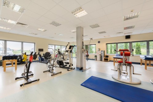 Strefa treningu medycznego z rowerami stacjonarnymi i urządzeniami do ćwiczeń ogólnousprawniających. 