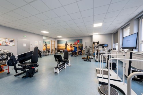 Sala rehabilitacyjna X-Rehab Poznań z nowoczesnym sprzętem do terapii ruchowej i stanowiskami diagnostycznymi. 