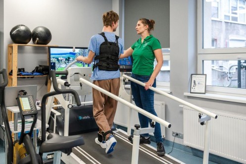 Terapia chodu na bieżni z poręczami pod okiem fizjoterapeutki w placówce w Poznaniu. 