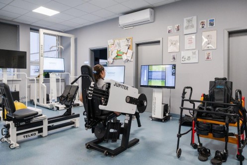 Pacjentka ćwiczy na urządzeniu Jupiter w sali treningu neurologicznego. 