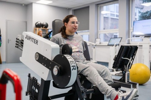 Trening kończyn dolnych na urządzeniu Jupiter w nowoczesnej sali rehabilitacyjnej. 