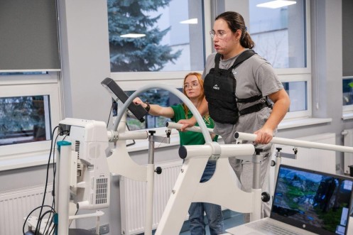 Terapia chodu na bieżni Zebris z asekuracją fizjoterapeutki i kamizelką obciążeniową. 